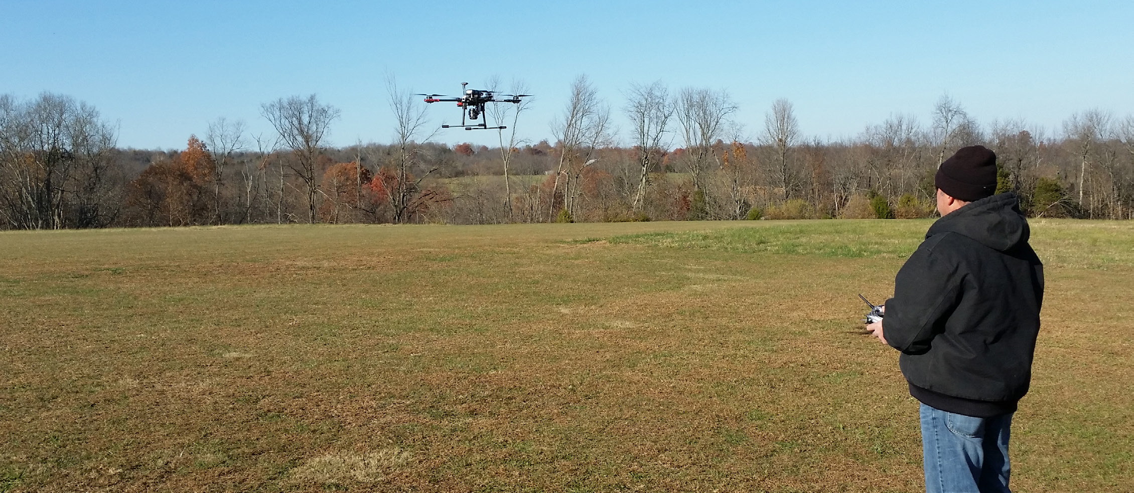 photo of a man flying a drone in a grassy field