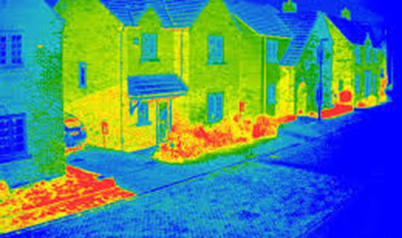 An infrared image of a house, sidewalk, and street